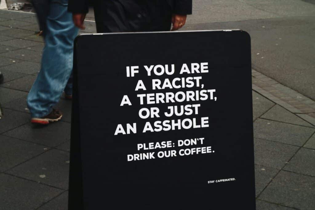 Black sign with white text about coffee.