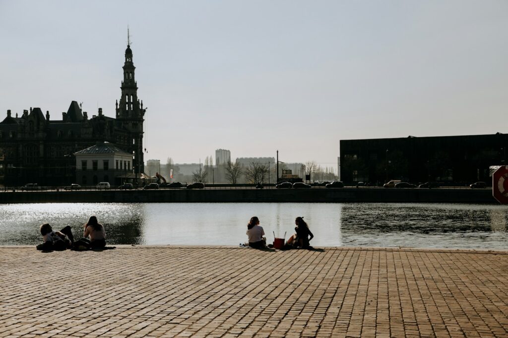 A group of people sitting next to a body of water