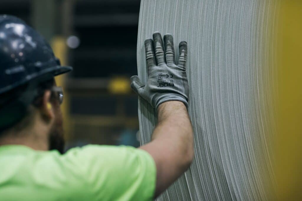 a man in a hard hat and safety gear working on a piece of metal