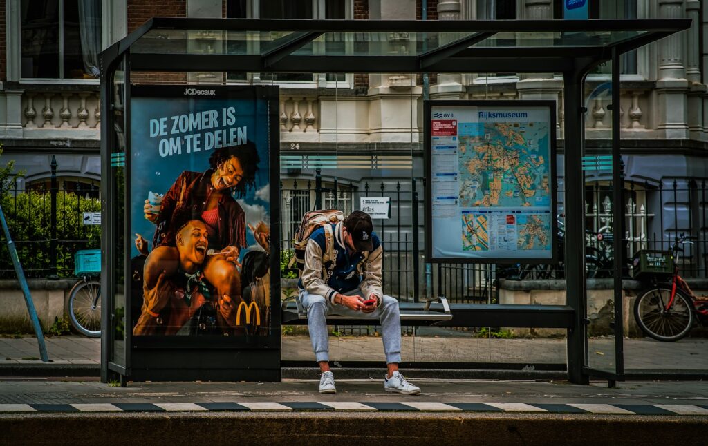 A man sitting on a bench in front of a bus stop