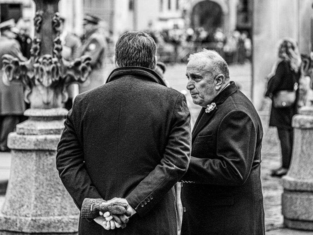 Monochrome photo of two men talking at an outdoor event, showcasing candid interaction.