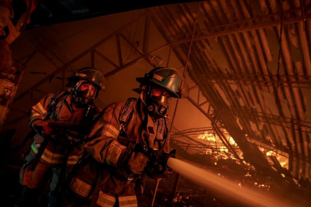Firefighters combat a blaze with a water hose.
