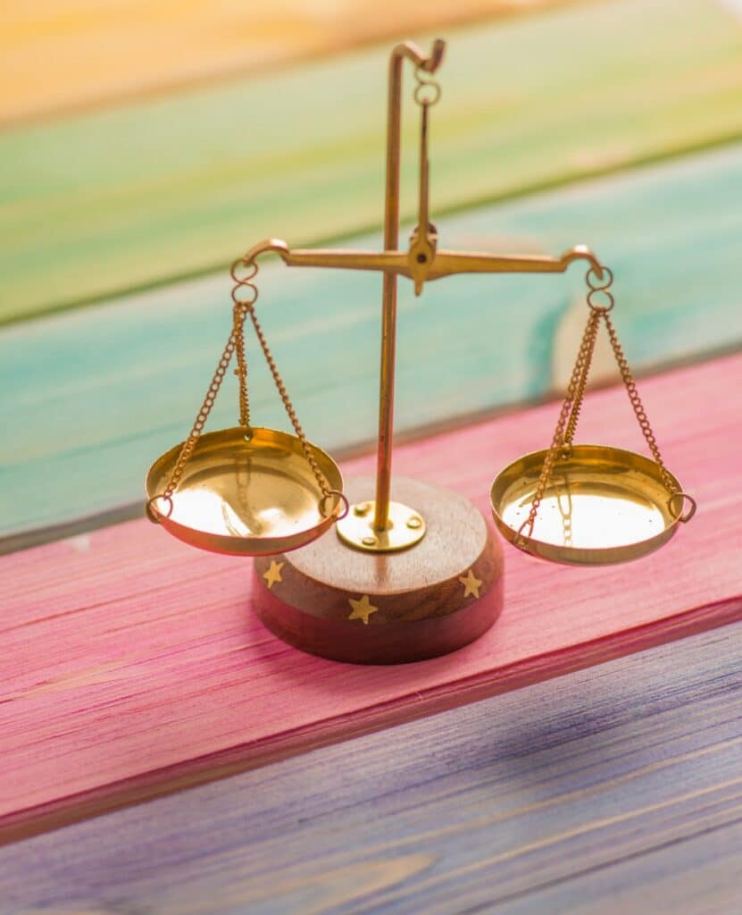 small gold balance scale on colorful wood