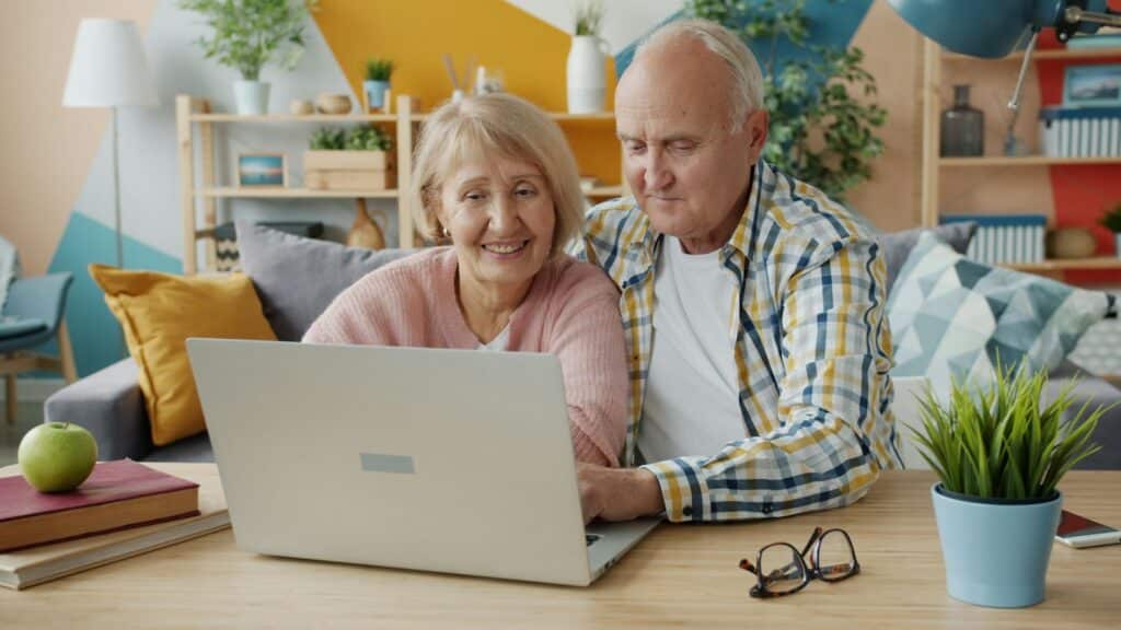 Elderly couple smiling while looking at laptop together